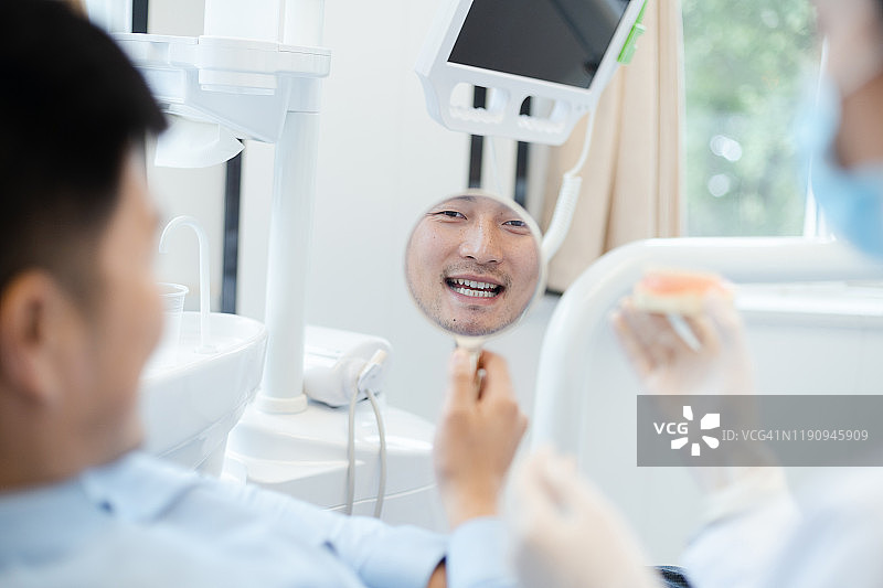 牙医对着镜子向病人展示他的新微笑图片素材