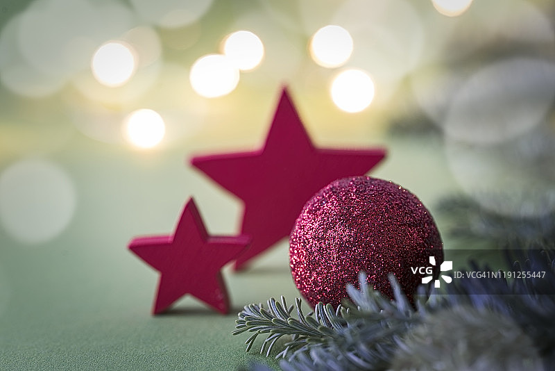红色的圣诞装饰物和红色的星星装饰在绿色的背景与复制空间。图片素材