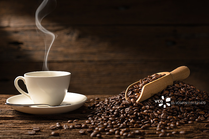 在古老的木制背景上，一杯带有烟和咖啡豆的咖啡图片素材