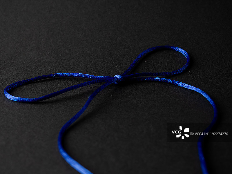 明亮的深蓝色丝线蝴蝶结在黑色的背景上图片素材