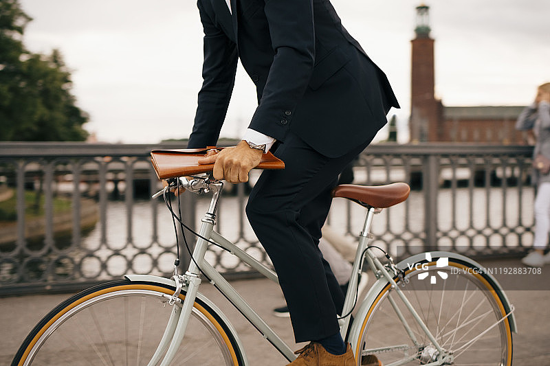 在城市的桥上骑自行车的商人图片素材
