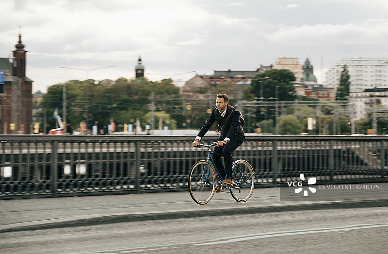 商人骑着自行车在城市街道上的天空图片素材