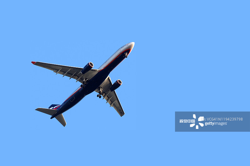 飞机航空公司航空公司着陆。飞机飞到降落时由底盘释放，以蓝天为背景，底部视图图片素材