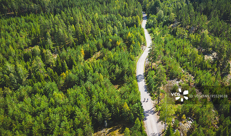 鸟瞰图两个骑自行车的人在一个小泥土路在芬兰的森林中间图片素材