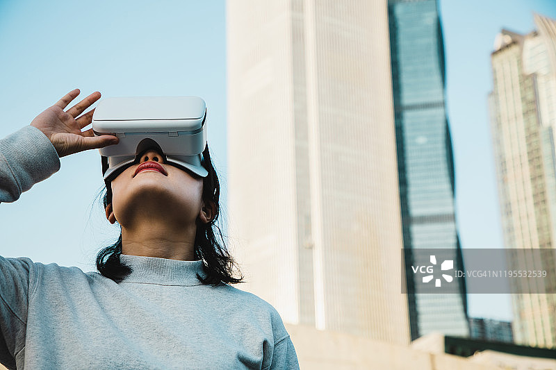 女人使用虚拟现实耳机在城市景观图片素材