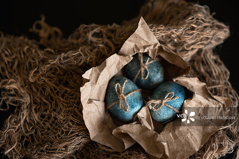 用手工在暗色背景上画上蓝色的巢中的复活节彩蛋。鸡和鹌鹑蛋天主教和东正教复活节图片素材