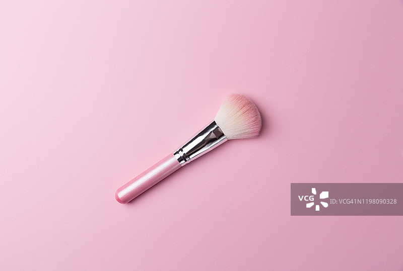 粉色专业化妆刷用于粉和眼影，隔离在粉色背景上。图片素材