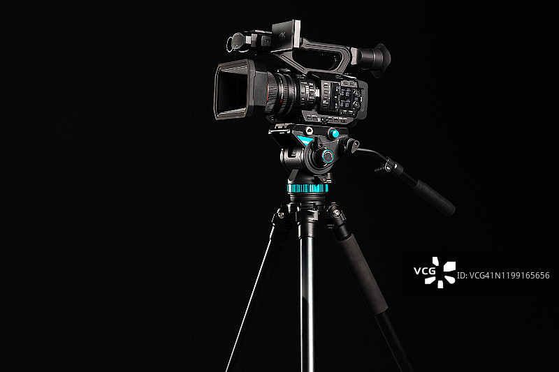 专业4K摄像机在相机三脚架上，黑色背景图片素材