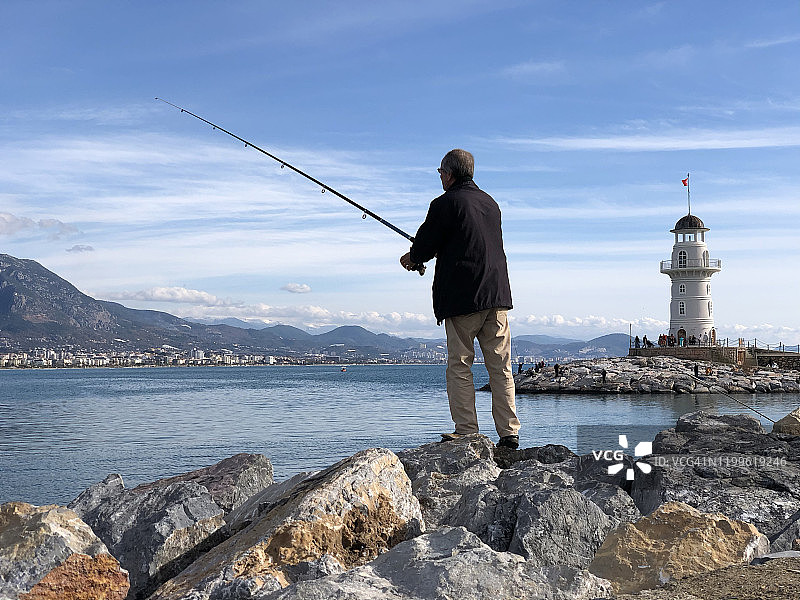 渔夫在灯塔附近钓鱼图片素材