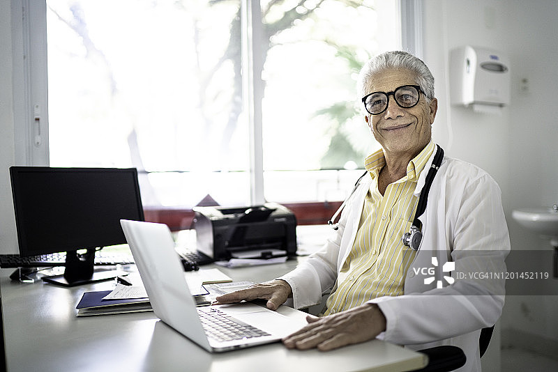 高级男医生在医院使用笔记本电脑的肖像图片素材