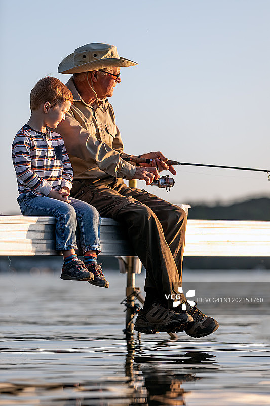 爷爷和孙子在夏天的日落钓鱼图片素材