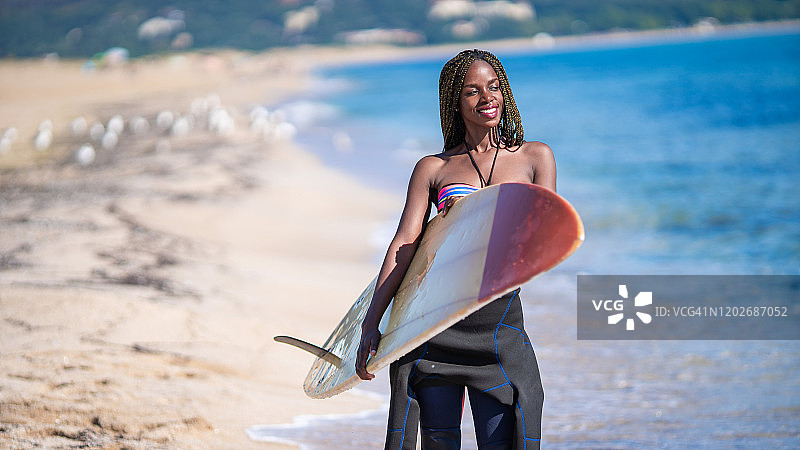 非洲妇女拿着冲浪板在海滩上行走图片素材