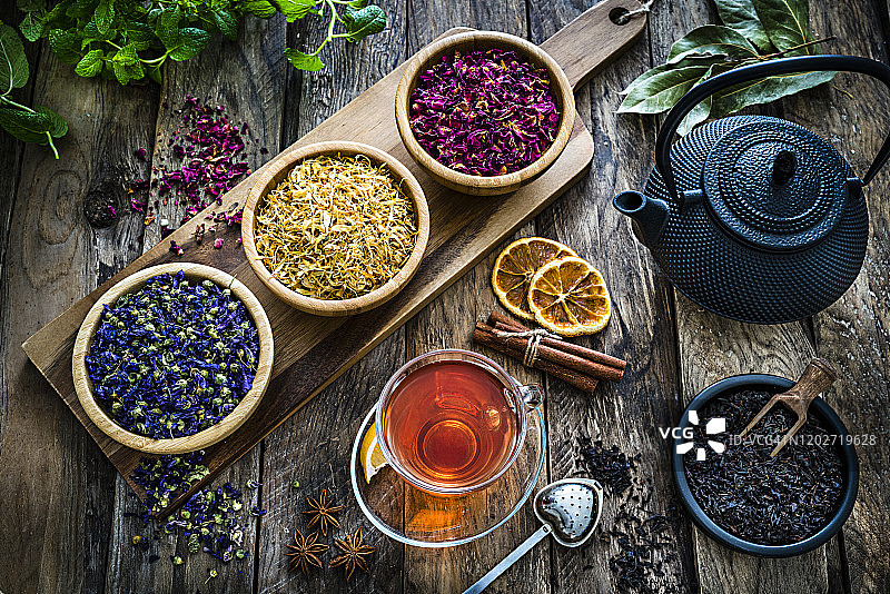 花草茶:放在质朴的木桌上，用玻璃杯盛满各种干茶叶和花图片素材