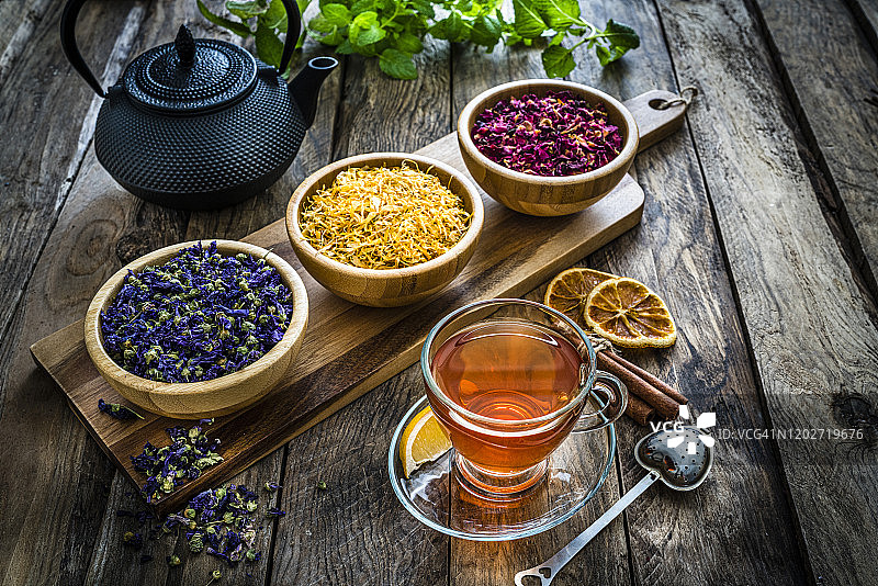 花草茶:放在质朴的木桌上，用玻璃杯盛满各种干茶叶和花图片素材