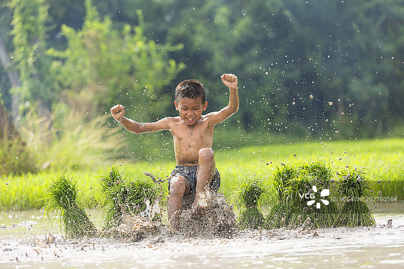 男孩喜欢在稻田里踢溅泥巴图片素材