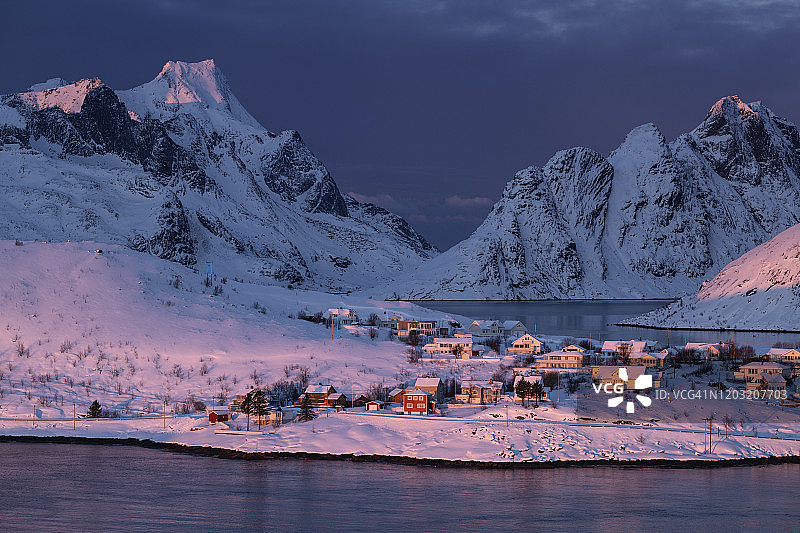 挪威罗浮敦群岛的勒内，莫斯克尼西，冬日黎明的粉红阳光，照耀着沿海的小村庄和山脉图片素材