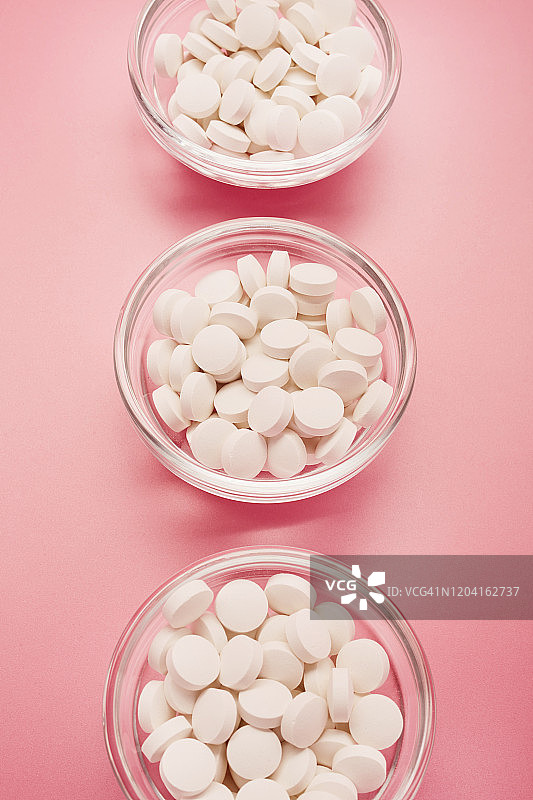 白色药丸在粉红色的背景下排成一排图片素材