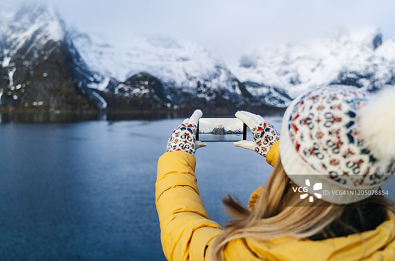 游客在挪威罗浮敦的哈姆诺伊用智能手机拍照图片素材