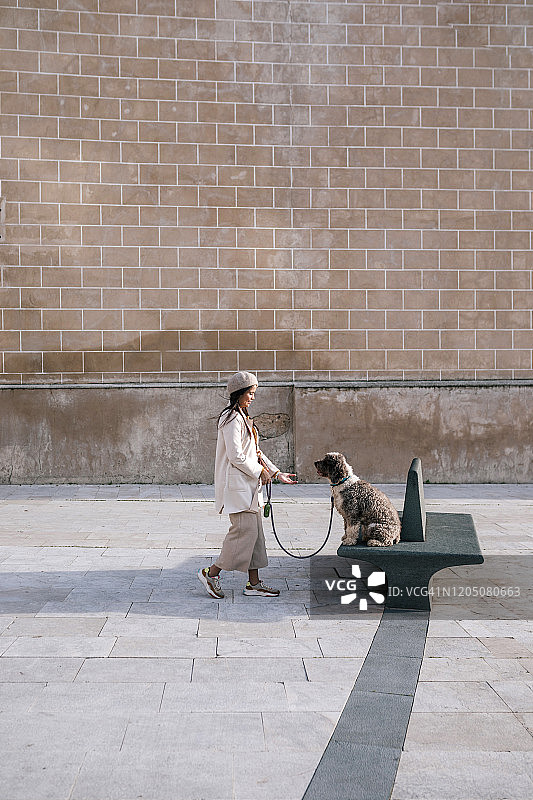 一个年轻女人和她的狗在城市的长椅上图片素材