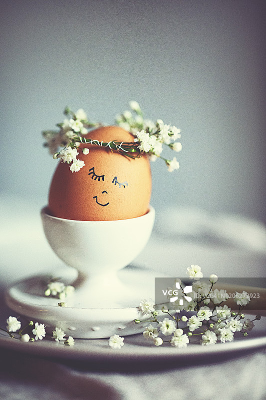 复活节早餐上画着有趣的脸和花环的蛋杯里的天然复活节蛋图片素材