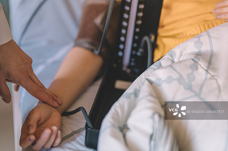 一位亚洲华人男医生在医院病房为他的女病人检查血压，在他的日常工作图片素材