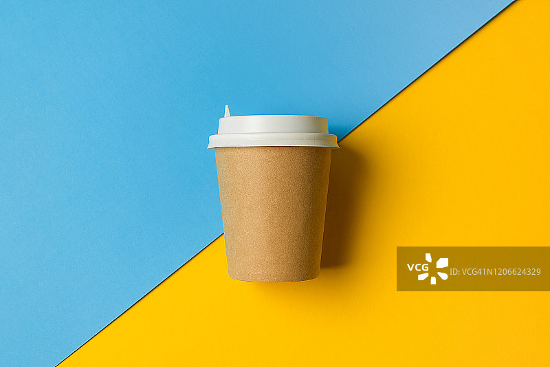 一次性纸杯与盖子的咖啡和茶在明亮的蓝色和黄色背景。休息时间。图片素材