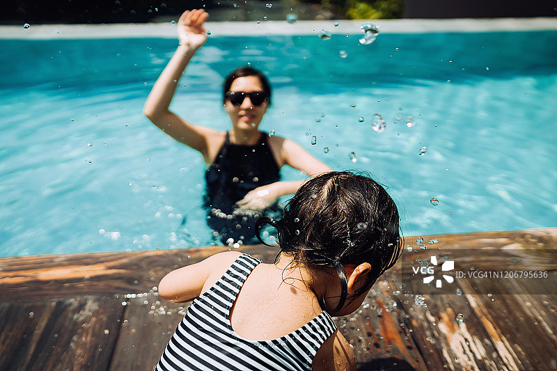 快乐的亚洲蹒跚学步的女孩享受家庭与母亲的时间，并在夏天的游泳池有乐趣图片素材