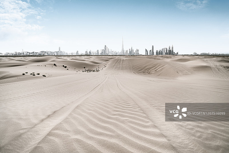 有轮胎痕迹的空旷沙漠和城市地平线图片素材