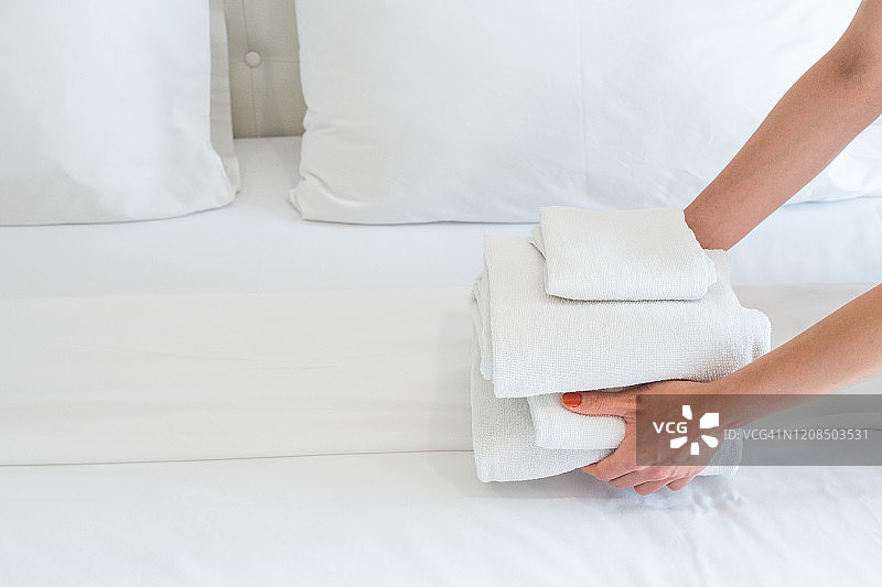 酒店服务员把毛巾堆在床上的镜头。图片素材