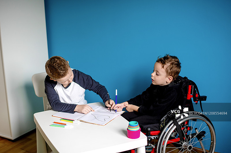 一个男孩和一个坐在轮椅上的男孩在家里学习图片素材