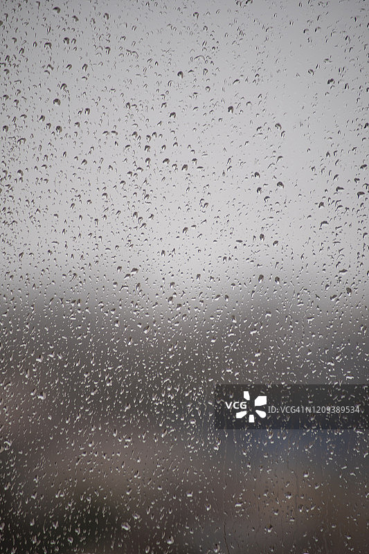 模糊的城市背景下，雨滴落在窗户上图片素材