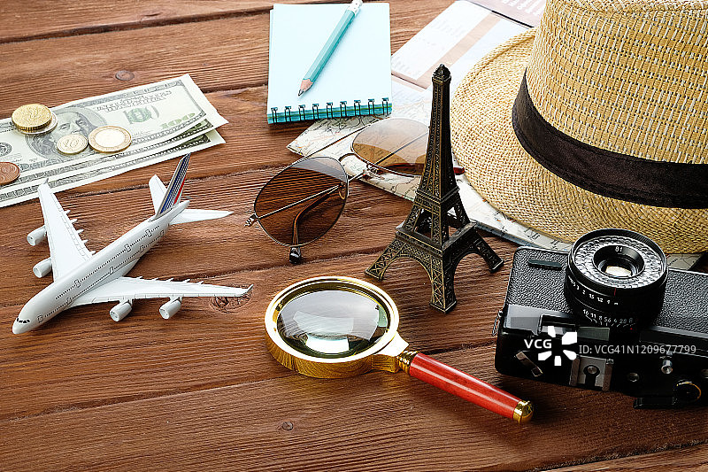 暑假物品:相机，太阳镜，钱，草帽和手机，地图和旅行计划。旅游布局-设置和配件的旅行者，在一个木制的背景。图片素材