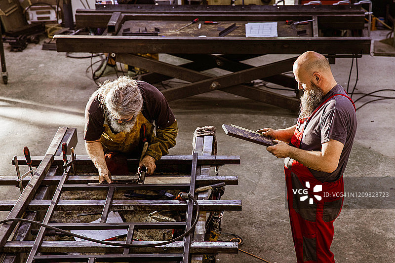 手工工人在车间测量钢材。图片素材