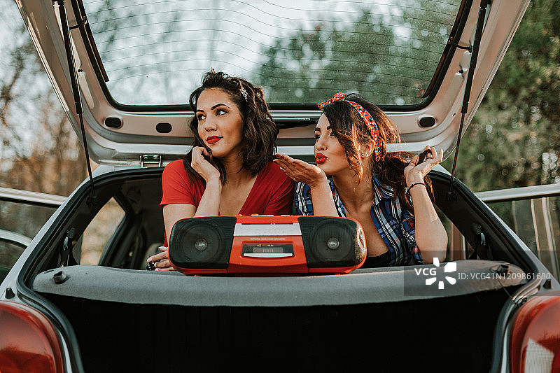 两个女人坐在车里听着扬声器里的音乐图片素材