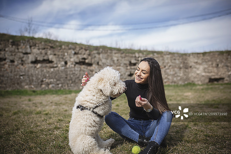 年轻的女人和她的狗在公园里玩图片素材