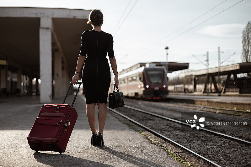 一个年轻女子在火车站拖着一个手提箱图片素材