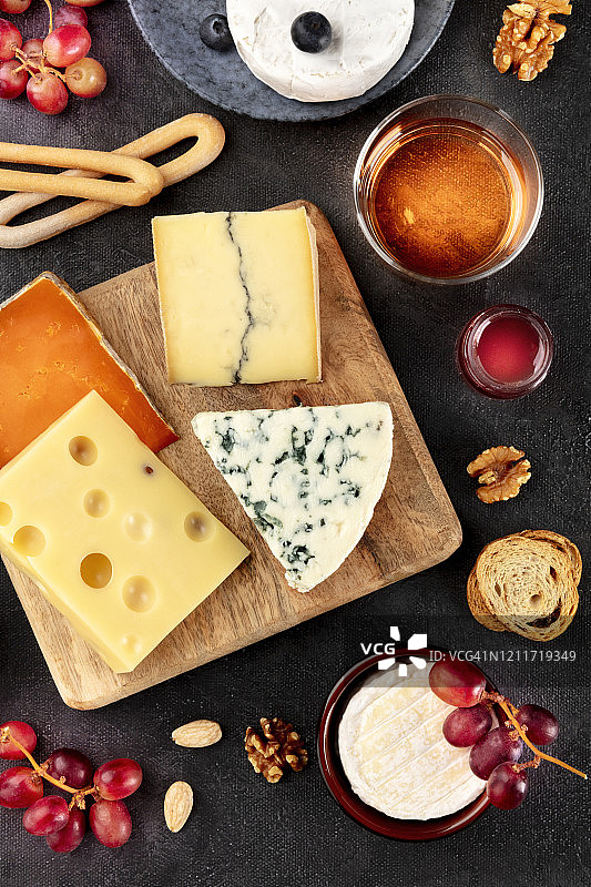 奶酪拼盘。蓝纹奶酪、布里干酪、埃曼塔尔奶酪等配酒，以黑色背景从上往下拍摄图片素材