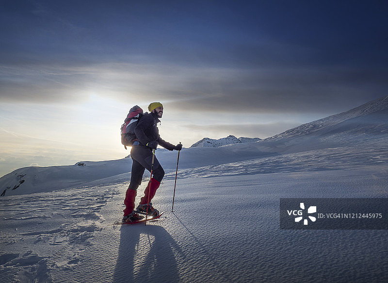 穿着雪鞋在雪坡上爬山的人图片素材