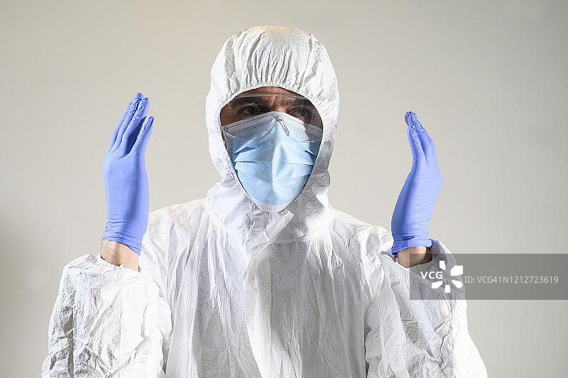 戴口罩、手套和防护服(防护服)的人或科学家举起双手。白色背景。冠状病毒和其他病毒及其分析。图片素材
