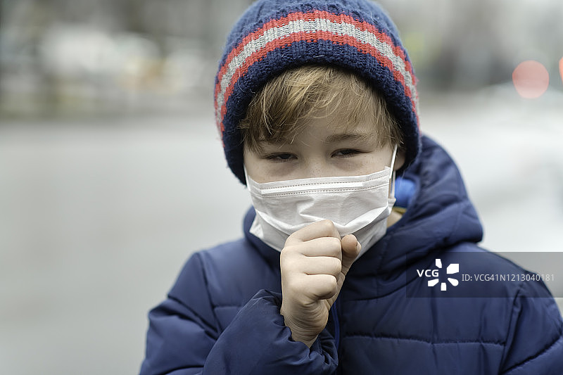 小男孩戴着医用防护口罩咳嗽图片素材