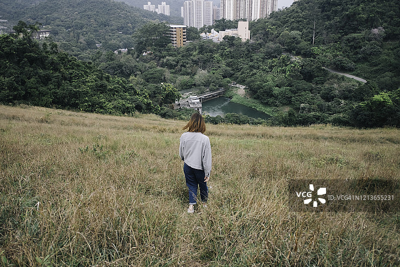 一只亚洲女性正沿着芒属植物的斜坡往下走，探索一条新的道路图片素材