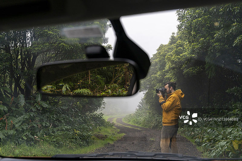 葡萄牙亚速尔群岛圣米格尔岛，一名男子在森林道路上拍摄汽车外的照片图片素材