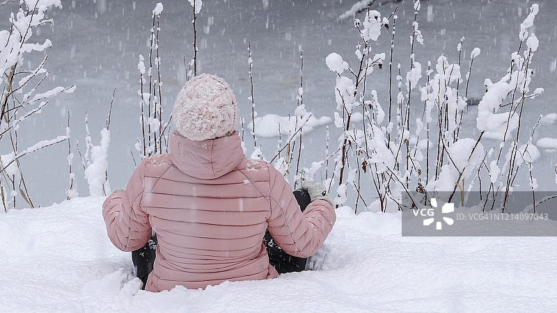 女徒步旅行者在白雪覆盖的河岸放松图片素材