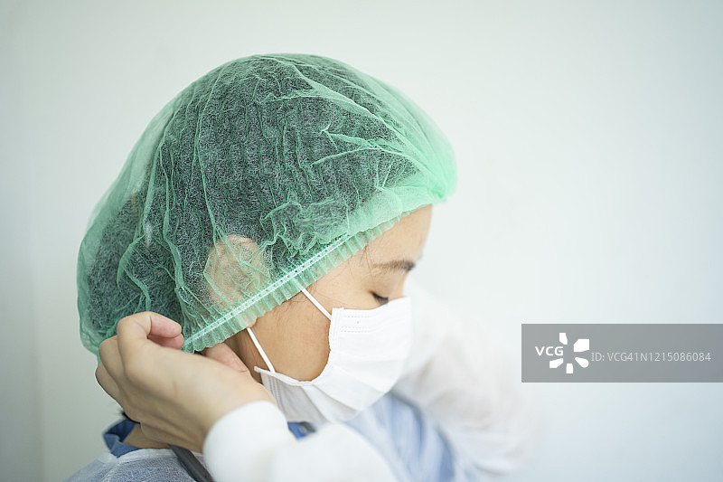 女医生教授如何佩戴医用口罩以保护Covid-19(冠状病毒)和pm2.5空气污染图片素材