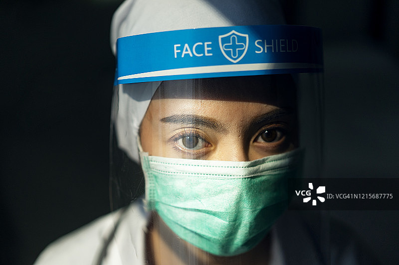 肖像亚洲女医生戴面罩和防护服，手持注射器应对冠状病毒或Covid-19疫情，Covid-19隔离的概念图片素材