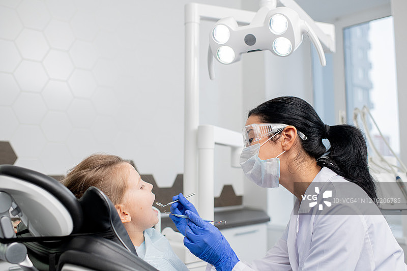 年轻的女牙医正在给小病人做口腔检查图片素材