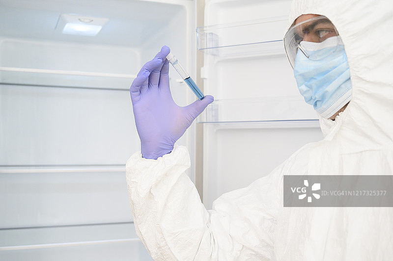 科学家手拿保护罩检查从冰箱里取出的医学样本。他穿着防护服(防护服)图片素材