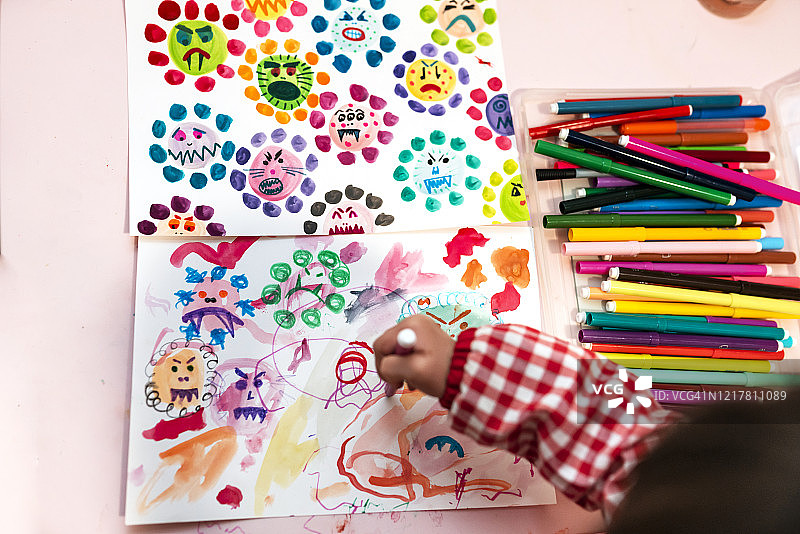 小女孩在家里用彩色笔画丑陋的病毒图片素材