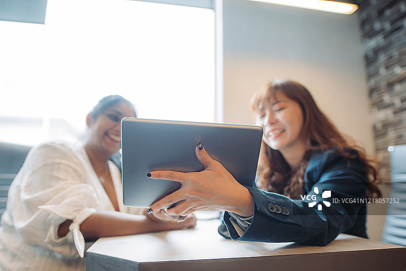 亚洲多种族微笑商务女性使用数字平板电脑在办公室讨论会议图片素材