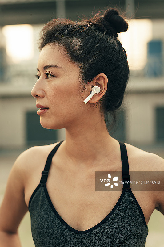 一个跑步者的肖像:适合亚洲女人的无线耳机准备跑步图片素材